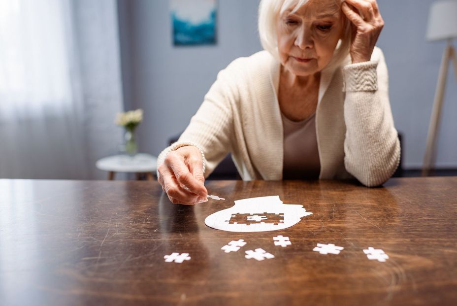 Una mujer afectada de demencia intentando acabar un puzzle. Bigstock 