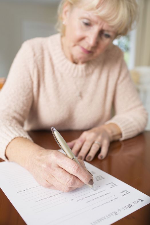 Mujer firmando su testamento. Fuente: Bigstock