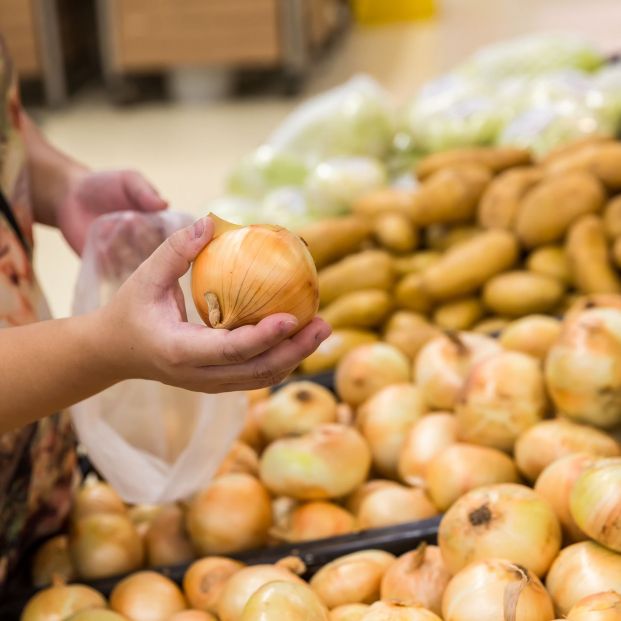 Cliente cogiendo cebollas en un supermercado. Fuente: Bigstock