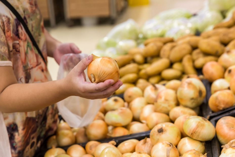 Cliente cogiendo cebollas en un supermercado. Fuente: Bigstock