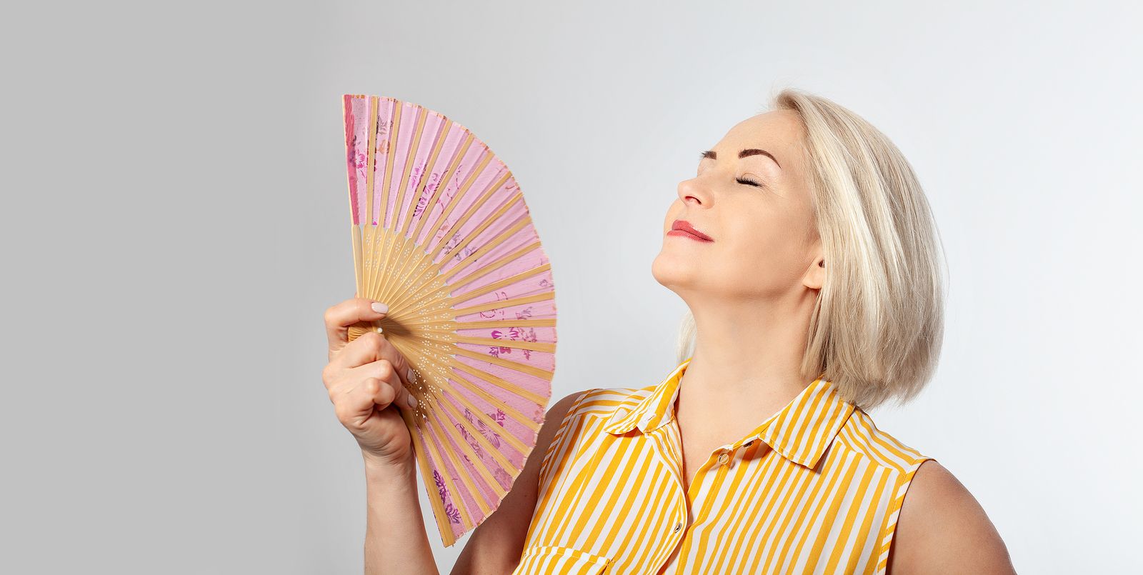 Una mujer de mediana edad combatiendo los sofocos. Bigstock