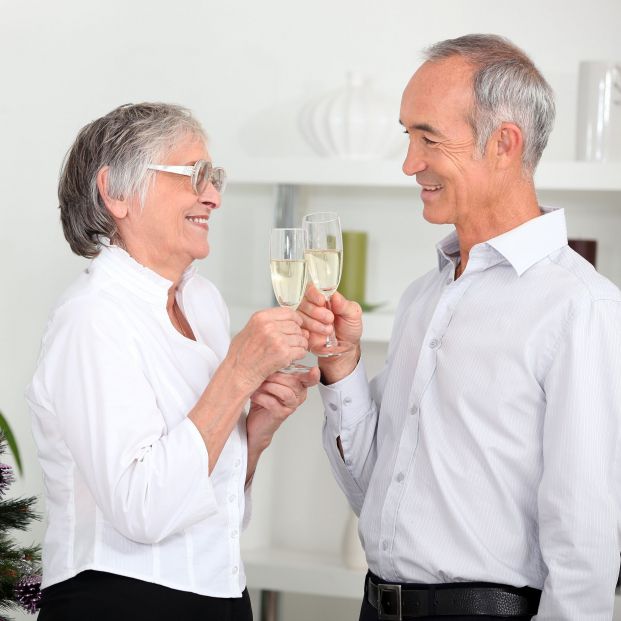 Dos personas brindando con una copa de cava en Navidad. Fuente: Bigstock