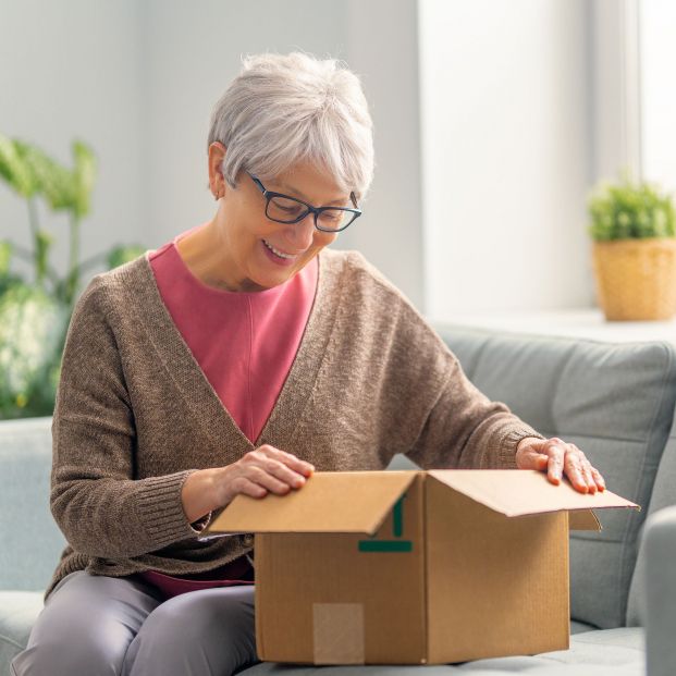 Una mujer abriendo un paquete que ha recibido a domicilio. Fuente: Bigstock