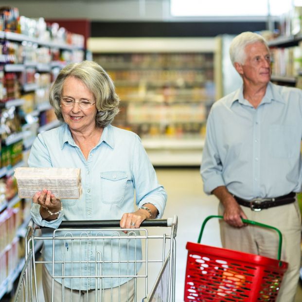 Dos personas comparando los precios de los productos en un supermercado. Fuente: Bigstock