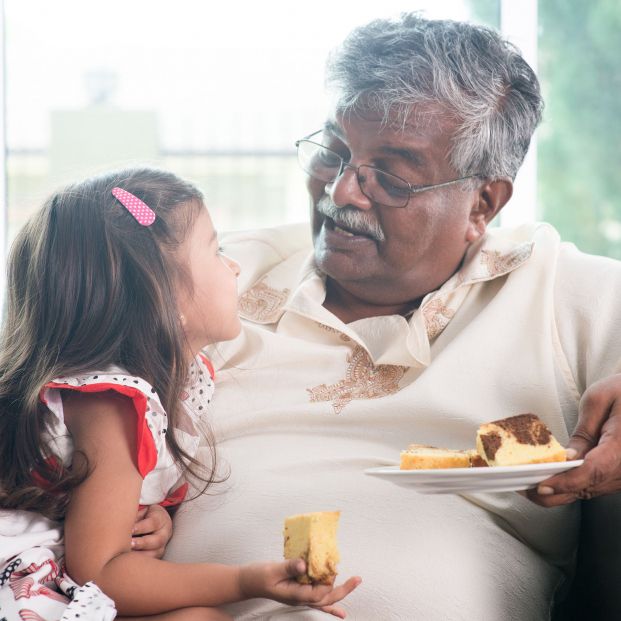 Un abuelo y su nieta comiendo una porción de tarta. Fuente: Bigstock