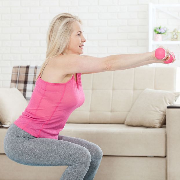 Mujer realizando sentadilla con mancuerna. Fuente: Bigstock