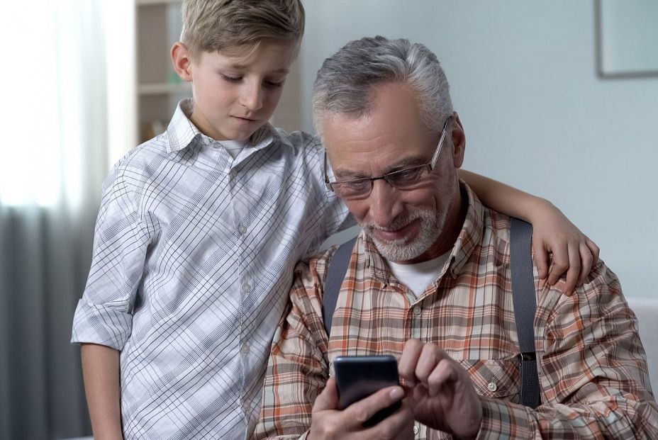 Un adulto mayor con su nieto usando el móvil Bigstock. Un adulto mayor con su nieto usando el móvil Bigstock.